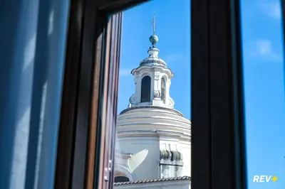 a tall white building with a tower in the reflection of a window at Mecenate Apartment Colosseum in Rome
