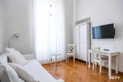 a white living room with a white couch and a desk at Mecenate Apartment Colosseum in Rome