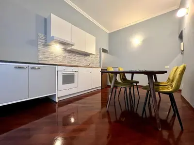 a kitchen with white cabinets and a table and chairs at Inn Sistina Home in Rome