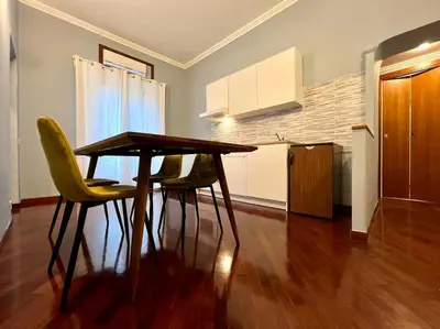a kitchen with a wooden table and two yellow chairs at Inn Sistina Home in Rome