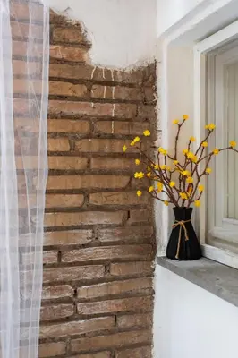 a brick wall with a vase of yellow flowers on a window sill at Lovely Nest by the Pantheon in Rome