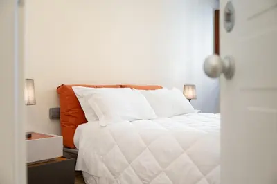 a bedroom with a white bed with an orange pillow at Mater Rooms & Suites in Rome