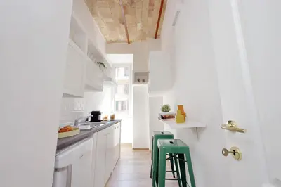 a kitchen with white cabinets and green stools at Principe Umberto Apartment in Rome