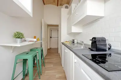 a kitchen with white cabinets and green stools at Principe Umberto Apartment in Rome