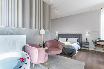 a bedroom with a bed and two chairs and a tub at Rome Plaza Suites, Luxury Collection in Rome