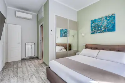 a white bedroom with a large bed and a mirror at Re di Roma Apartment in Rome