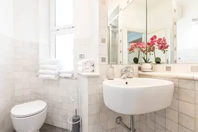 a white bathroom with a sink and a toilet at Colosseo Terrace Apartment in Rome
