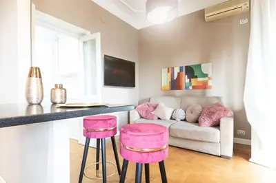 a living room with pink stools and a couch at Colosseo Terrace Apartment in Rome