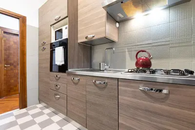 a kitchen with wooden cabinets and a red tea kettle at Amazing Art Déco Apartment Pantheon in Rome