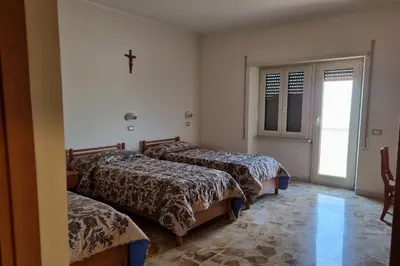 three beds in a room with a cross on the wall at Palazzo Sant'Antonio in Rome