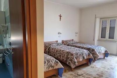 three beds in a room with a cross on the wall at Palazzo Sant'Antonio in Rome