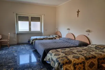 a room with three beds and a cross on the wall at Palazzo Sant'Antonio in Rome