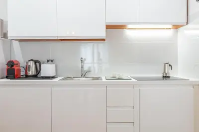 a white kitchen with white cabinets and a sink at Barberini 3 BDR Apartment in Rome