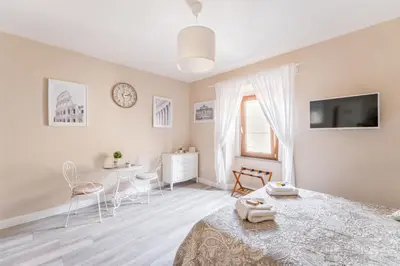 a white bedroom with a bed and a table and chairs at The small nest at Coliseum in Rome