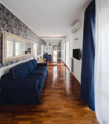 a living room with a blue couch and wooden floors at New opening San Pietro roof apartament in Rome