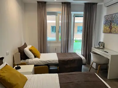 a hotel room with two beds and a desk at Anastasio Vatican Rooms G H in Rome