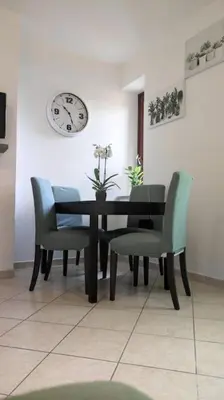 a dining room table with chairs and a clock on the wall at l'altra casetta dei Quintili in Rome