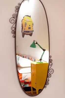 a mirror reflecting a bedroom with a van on the wall at MyWay Colosseo Apartment in Rome