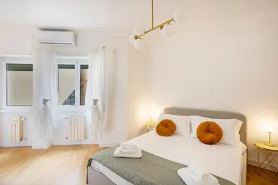 a white bedroom with a bed with orange pillows on it at Re di Roma - Charme Apartment in Rome