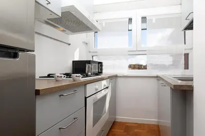a white kitchen with white cabinets and a window at Re di Roma - Charme Apartment in Rome