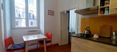 a kitchen with a table and red chairs and a table at Terrace Apartment On The Monuments Of Rome in Rome