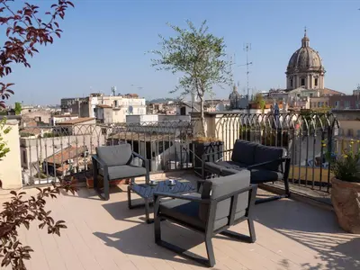 a patio with chairs and a table on a balcony at Terrace Apartment On The Monuments Of Rome in Rome