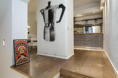 a kitchen with white cabinets and a tv on the wall at Trevi Loft in Rome