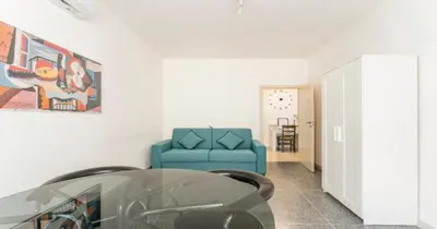 a living room with a blue couch and a glass table at Massi Vatican House in Rome