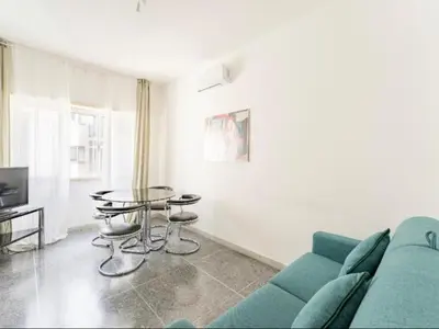a living room with a blue couch and a glass table at Massi Vatican House in Rome