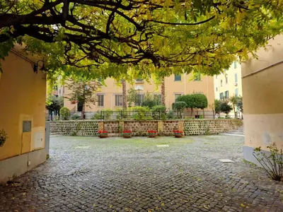 a courtyard in a building with red flowers at Nox Romana Apartments - Vatican - Threeroom Apt with 2 Bathroom in Rome