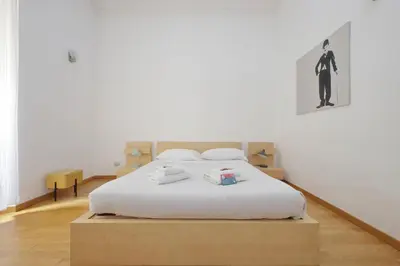a bedroom with a large white bed with a wooden headboard at Vatican Spacious Modì Apartment in Rome