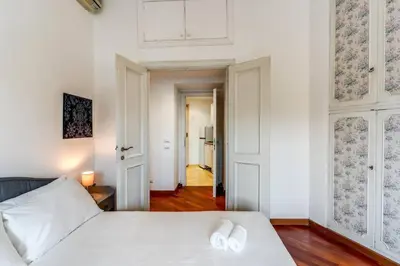 a bedroom with a white bed and a hallway at Splendid flat on the Tiber river in Rome
