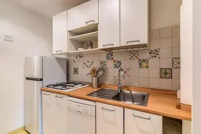 a kitchen with white cabinets and a sink and a refrigerator at Splendid flat on the Tiber river in Rome