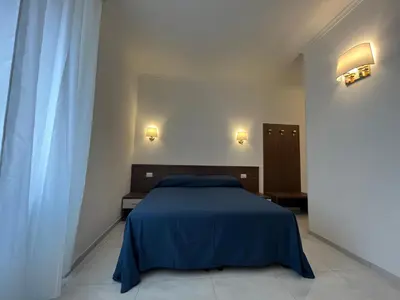 a bedroom with a blue bed and two lights on the wall at Giovanni Guest House in Rome