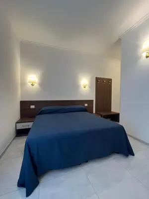 a bedroom with a blue bed and two lights on the wall at Giovanni Guest House in Rome