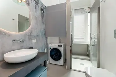 a bathroom with a sink and a washing machine at Aletheia Èlite - Elegant 2 BR in Rome