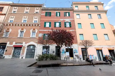 a group of buildings with people sitting in front of them at La Pietra al Pigneto in Rome
