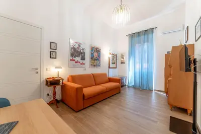 a living room with an orange couch and a refrigerator at Casa Marin - Metro Malatesta in Rome