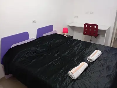 a bedroom with a bed with black sheets and two chairs at Pigneto House in Rome