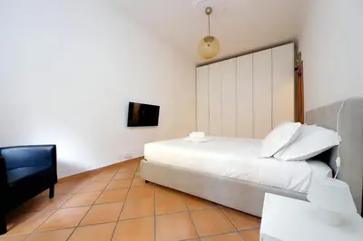 a bedroom with a white bed and a black chair at suity I cozy anglona apartment in Rome