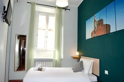 a bedroom with two white beds and a green wall at AmareRomaRooms in Rome