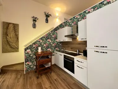a kitchen with white cabinets and flowers on the wall at Relais Romagnosi in Rome