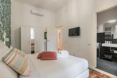 a white bedroom with a white bed and a mirror at New Prati Luxury Apartment in Rome