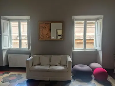 a living room with a couch and a mirror and windows at Warm Charming Apartment in Campo de Fiori in Rome