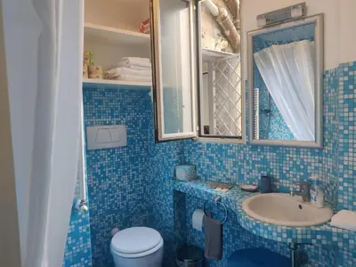 a blue tiled bathroom with a sink and a toilet at Warm Charming Apartment in Campo de Fiori in Rome