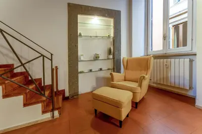 a living room with a chair and a stool at Ciambella Arch Apartment for 6 people @Largo Argentina in Rome