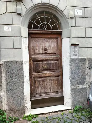a large wooden door in a building with an arch at Quiet apartment in the heart of Trastevere in Rome