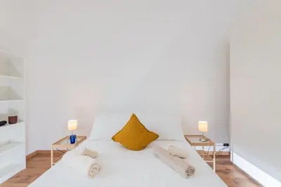 a white bedroom with a white bed with yellow pillows at Bell Appartamento in Rome