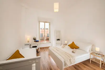 a white bedroom with a bed and a desk at Bell Appartamento in Rome