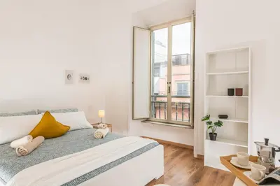 a white bedroom with a large window and a bed at Bell Appartamento in Rome